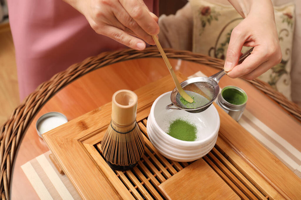 Master preparing matcha drink at wooden table, closeup. Tea ceremony - Zdjęcie, obraz