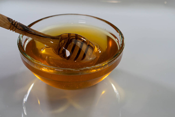 Piatto ciotola di vetro con cucchiaio di legno di miele, dipper, sfondo bianco, spazio copia - Foto, immagini