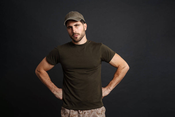 Confident masculine military man posing and looking at camera isolated over black background - Photo, image