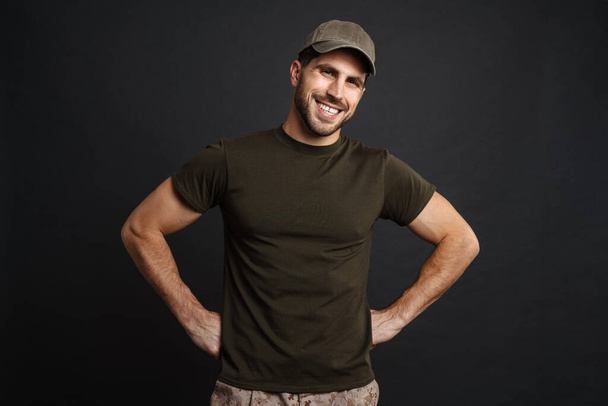Happy masculine military man smiling and looking at camera isolated over black background - Foto, Imagen