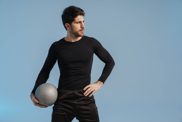 Handsome athletic sportsman posing with medicine ball isolated over blue background - Φωτογραφία, εικόνα