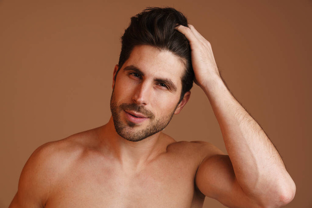 Shirtless masculine man posing and looking at camera isolated over beige background - Foto, imagen