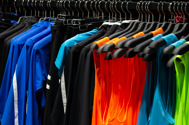 Photo de t-shirts et chemises sport multicolores sans manches suspendus sur le porte-magasin. - Photo, image