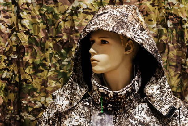 Photo of hunting store male mannequin standing in forest masking camouflaged jacket. - Fotografie, Obrázek
