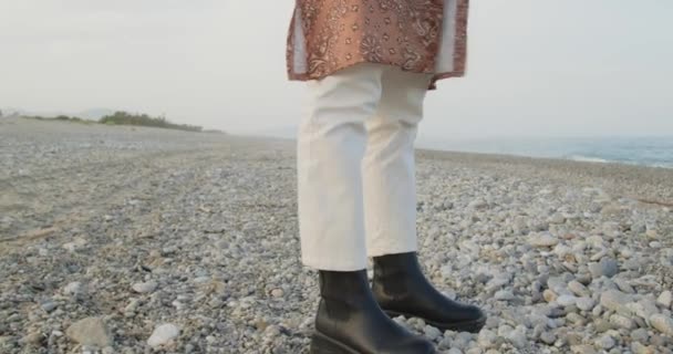 Siyah çizmeleri ve beyaz pantolonu olan güzel bir İtalyan kızı yazın denizde yürüyor. - Video, Çekim