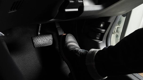 Foot pressing foot pedal of a car to drive. Accelerator and brake pedal in a car. Driver driving the car by pushing accelerator and break pedals of the car. inside vehicle. control pedal. Close up. - Foto, imagen
