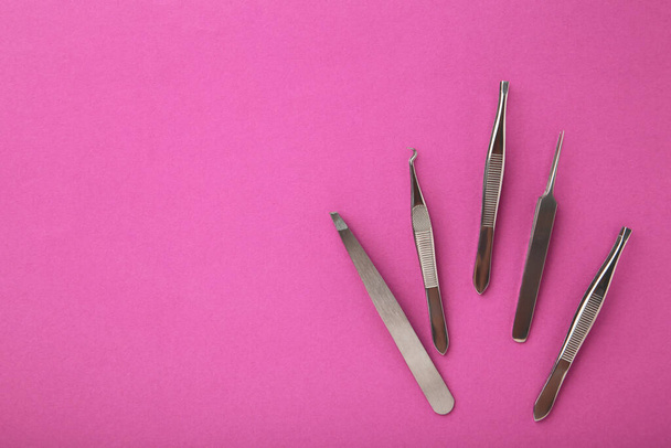 Concetto di bellezza e moda - strumenti per la procedura di estensione delle ciglia. Pinzette su sfondo rosa. Mockup del copyspace. Vista dall'alto - Foto, immagini