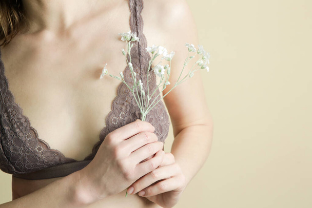 Kobieta w koronkowym staniku trzymająca kwiat. Zapobieganie chorobom piersi, zdrowie kobiet i koncepcja samoopieki. - Zdjęcie, obraz