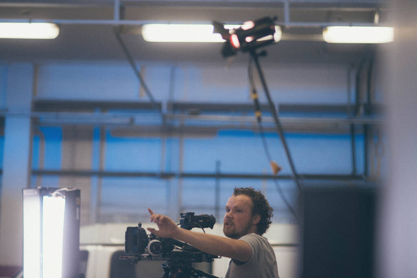 Operatőr kamerával a kezében a forgatáson. Film-, reklám- vagy TV-sorozat forgatásán dolgozó professzionális videós. Filmkészítési folyamat zárt térben, stúdióban - Fotó, kép