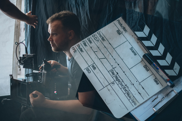Director of photography with a camera in his hands on the set. Professional videographer at work on filming a movie, commercial or TV series. Filming process indoors, studio - Fotografie, Obrázek