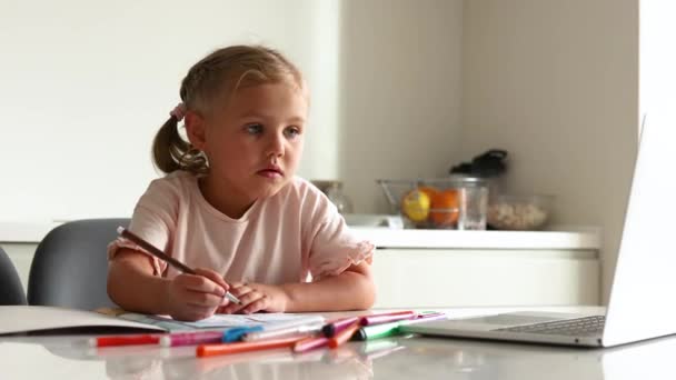 Menina loira bonito sentado em casa na cozinha com laptop. Educação à distância para crianças. Crianças e gadgets - Filmagem, Vídeo