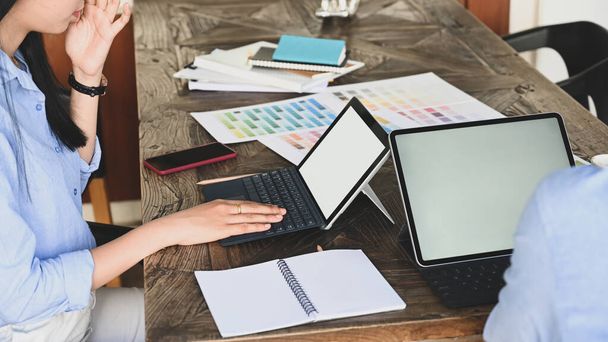 Vágott kép grafikus csapat dolgozik együtt számítógépes tablet és színes útmutató / információ a fa tárgyalóasztal felett vintage iroda, mint a háttér. - Fotó, kép