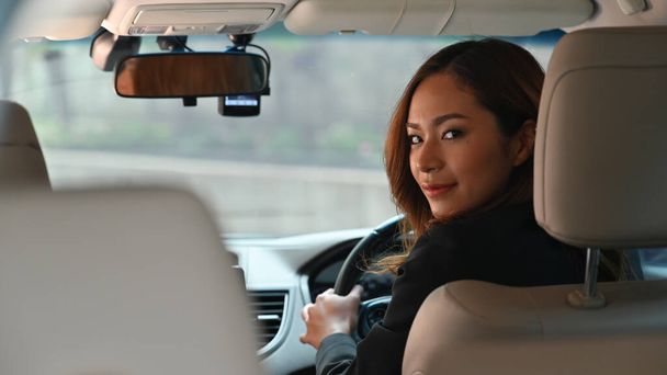 Foto de una joven mujer de negocios hermosa mientras conduce un coche de lujo que va a su lugar de trabajo. Concepto de transporte personal. - Foto, imagen
