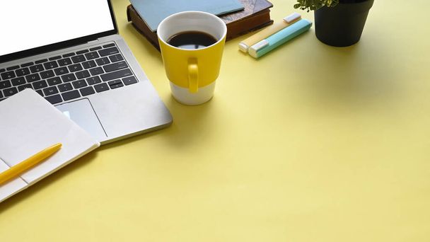 Вид зверху зображення барвистого робочого місця, яке повне документа, чашки кави, ноутбука, ручки, маркерні ручки та комп'ютерний ноутбук з білим порожнім екраном
. - Фото, зображення