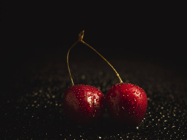 Frische Kirschen mit Wassertropfen auf dunklem Hintergrund - Foto, Bild