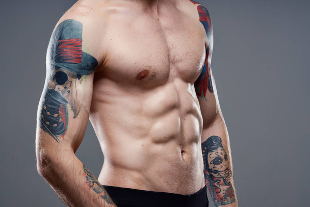 sportieve man met opgepompte buikspieren bijgesneden weergave van tatoeage op armen close-up - Foto, afbeelding