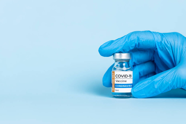 Doctor hand in protective glove holds Coronavirus Covid-19 Vaccine glass bottle. Coronavirus 2019-nCoV concept - Фото, изображение