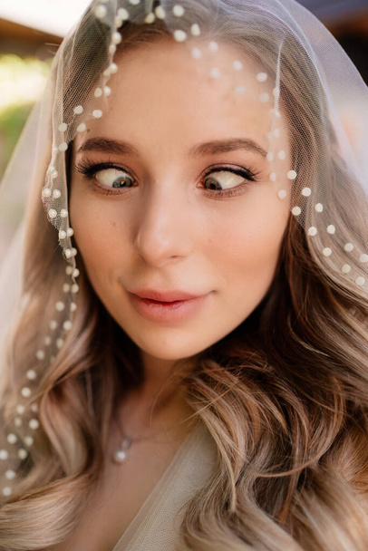 funny bride with long wavy hair under the veil outside. Wedding make-up.  - 写真・画像
