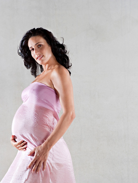 Donna incinta avvolta in seta rosa
 - Foto, immagini