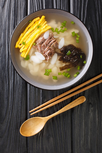 伝統的な新年の料理Tekgukは、スライスした餅で作られたスープです,通常、テーブルの上にボウルに牛肉のスープを閉じ.アボフからの垂直方向のトップビュー - 写真・画像