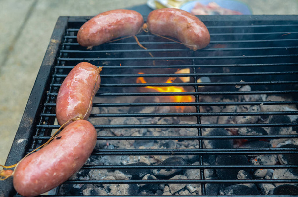 A closeup shot of traditional Argentinian Asado, sausages cooking on the grill at a street - Foto, imagen