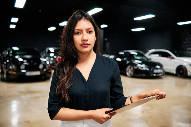 joven vendedora latina vendiendo coches de lujo - Foto, imagen