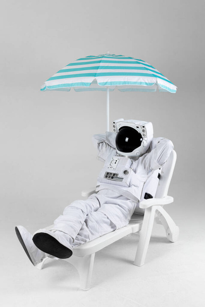 astronaut resting under parasol, white background - Fotó, kép