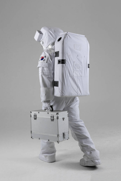 Astronaut walking holding a hard brief case, a white background - Foto, Bild