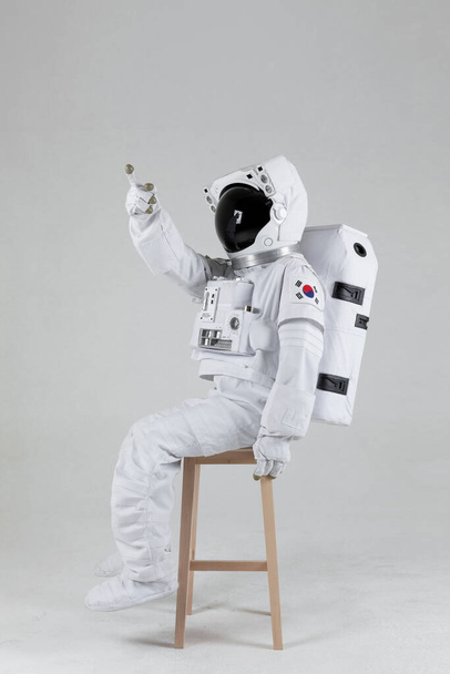 Astronaut sitting on a wooden chair, white background - Фото, зображення