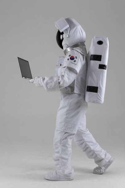 astronaut walking while using laptop computer device, white background - Foto, imagen