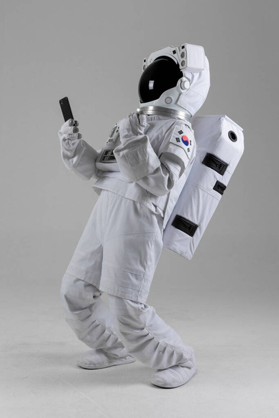 happy Astronaut holding smart phone in hand, white background - Foto, Imagen