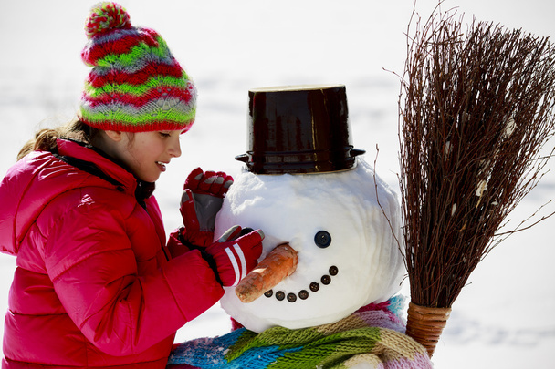 Зимнее веселье, счастливый ребенок играет со снеговиком
 - Фото, изображение