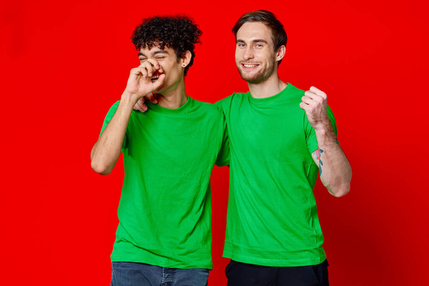 Χαρούμενοι φίλοι πράσινα μπλουζάκια συναισθήματα επικοινωνία αγκαλιά φιλία - Φωτογραφία, εικόνα