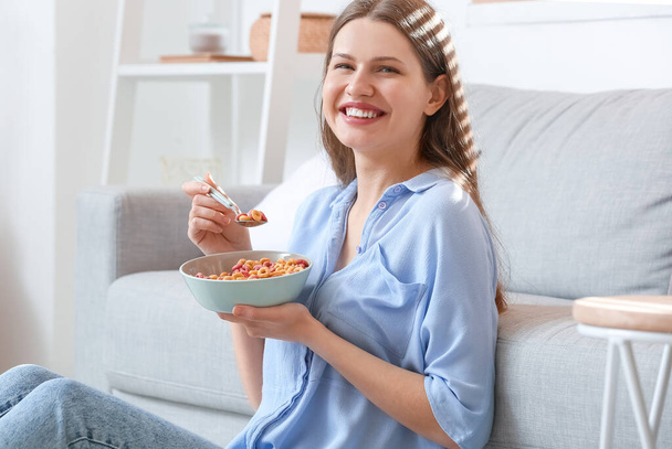 Beautiful young woman eating cornflakes at home - Фото, зображення