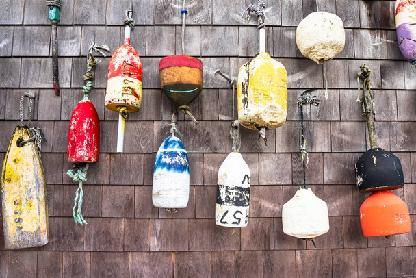 Close up of old lobster buoys hanging on a weathered wooden wall of a fishing hut in a harbour. Cape Cod, MA, USA. - Photo, Image