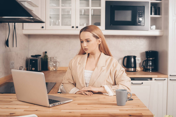 Woman behind laptop works from home.  The student submits a report online. The girl teaches courses, lectures on the Internet. Freelance earnings. The model is gesturing - Zdjęcie, obraz