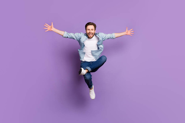 Full body photo of happy positive cheerful young man jump up good mood weekend isolated on violet color background - Фото, изображение