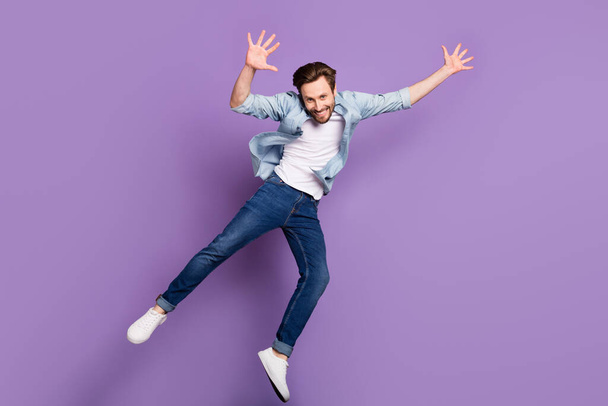 Full length photo of happy cool positive young man jump up good mood isolated on violet color background - Zdjęcie, obraz