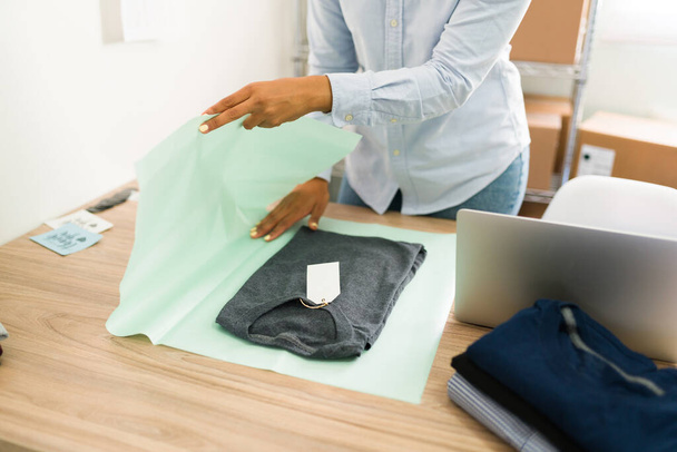 Geschäftsinhaberin, die an ihrem Bekleidungsgeschäft arbeitet. lateinische junge Frau bereitet ein Paket mit T-Shirt für eine Online-Bestellung vor - Foto, Bild