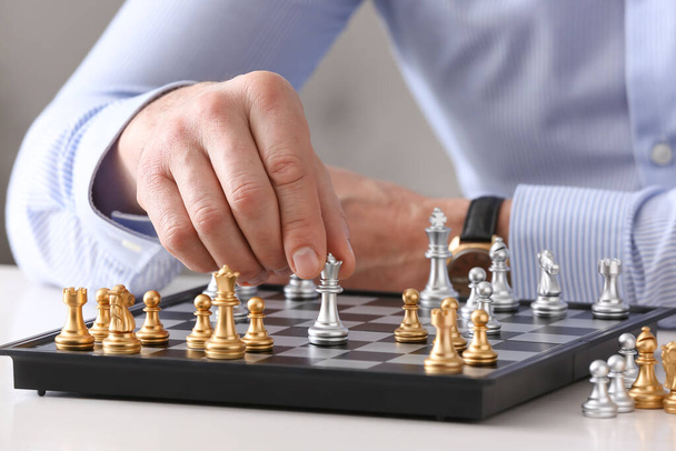Чоловік грає в шахи на білому столі
 - Фото, зображення