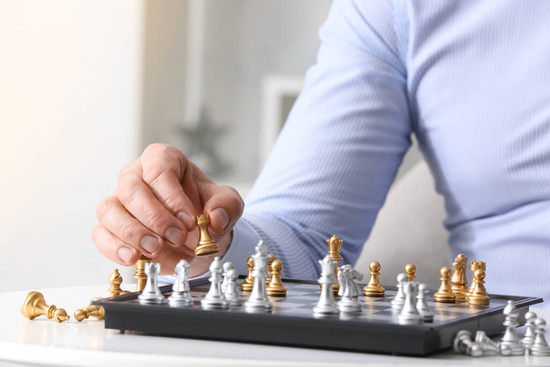 Человек играет в шахматы на белом столе - Фото, изображение