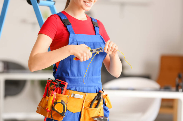 Young female electrician with pliers in room - Foto, afbeelding
