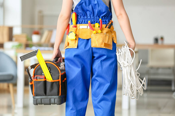 Young female electrician with tools in room - Foto, afbeelding