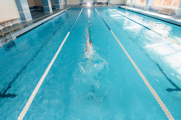 A young athlete trains and prepares for swimming competitions in the pool. Healthy lifestyle. - Foto, Imagen
