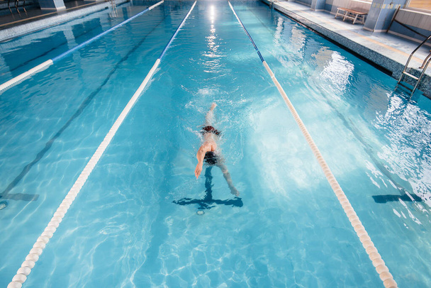 A young athlete trains and prepares for swimming competitions in the pool. Healthy lifestyle. - Foto, afbeelding