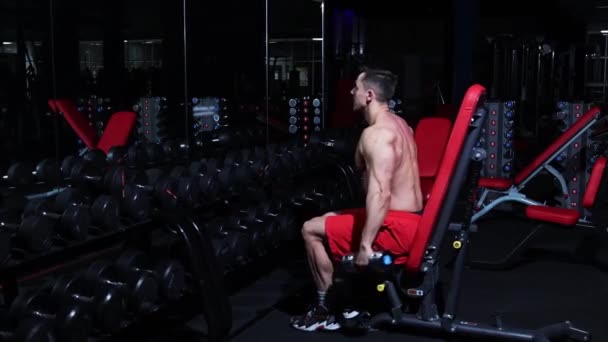 Gym-Training - gepumpter Mann sitzt vor Spiegel und hebt Hanteln - Filmmaterial, Video