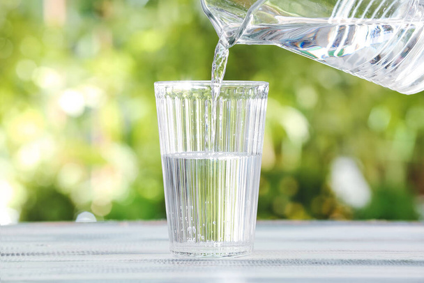 Nalévání sladké vody ze sklenice do skla na stůl venku, detailní záběr - Fotografie, Obrázek
