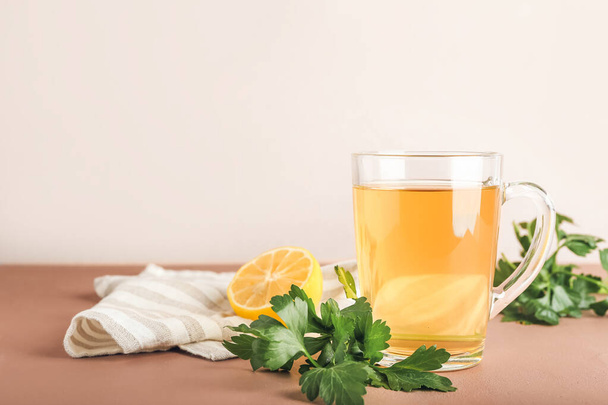 色の背景に熱いお茶、パセリとレモンのカップ - 写真・画像
