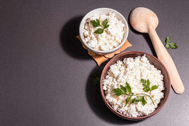 Cottage cheese in a ceramic bowl. Homemade milk product on a deep plate. Stone concrete background, top view, flat lay - Φωτογραφία, εικόνα