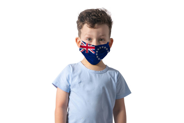 クック諸島の旗を持つ呼吸器。白い男の子は白い背景に隔離された医療面のマスクに置きます. - 写真・画像